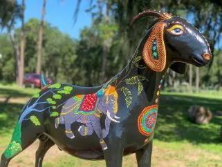 Colorful painted goat sculpture displayed outdoors in a park
