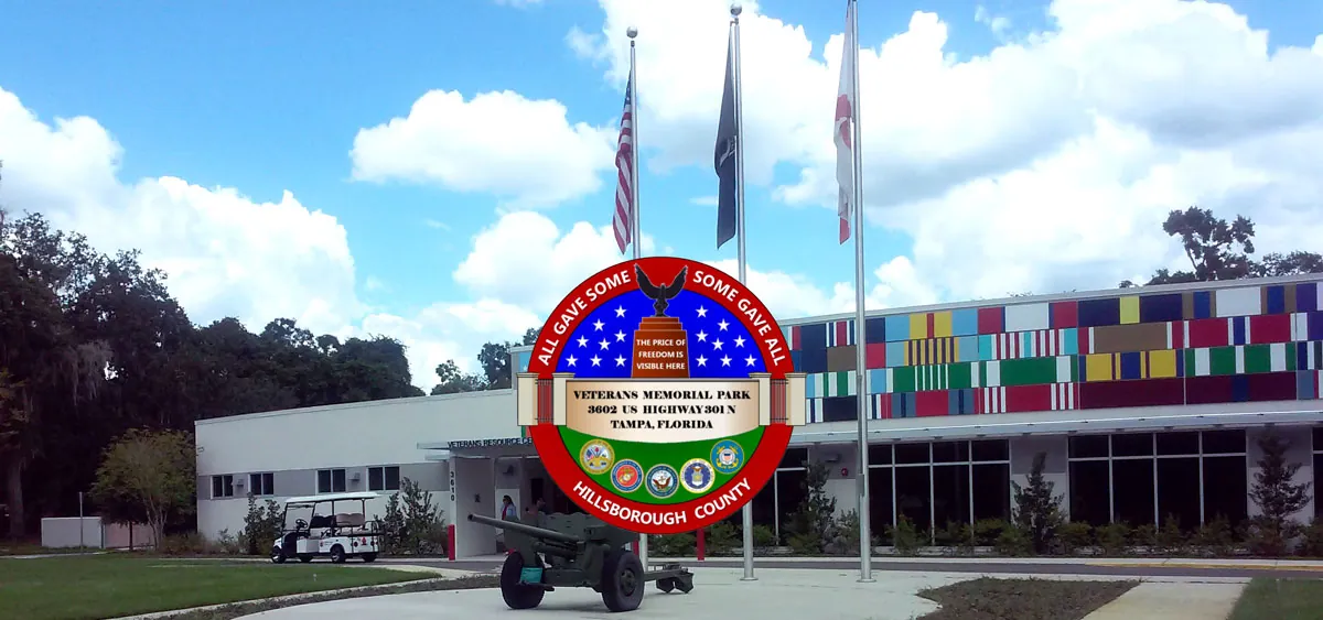 Government building with American and state flags, and a round commemorative emblem in front