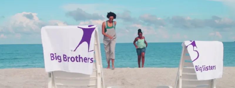 Big Brothers Big Sisters banner on a beach with two people in the background