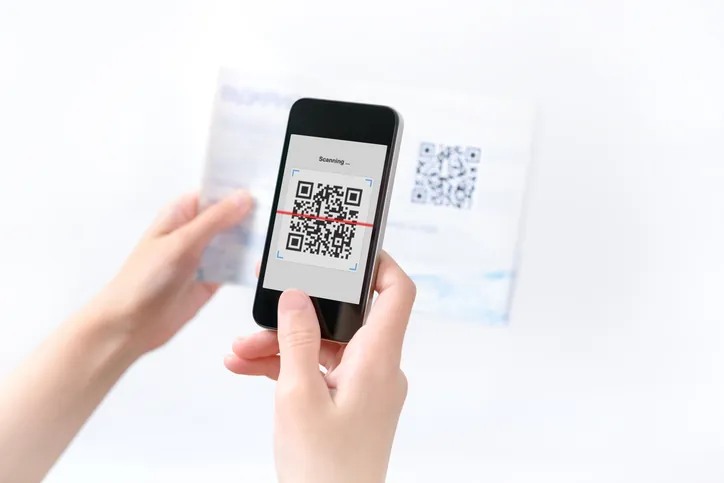 Hand holding a smartphone displaying a QR code