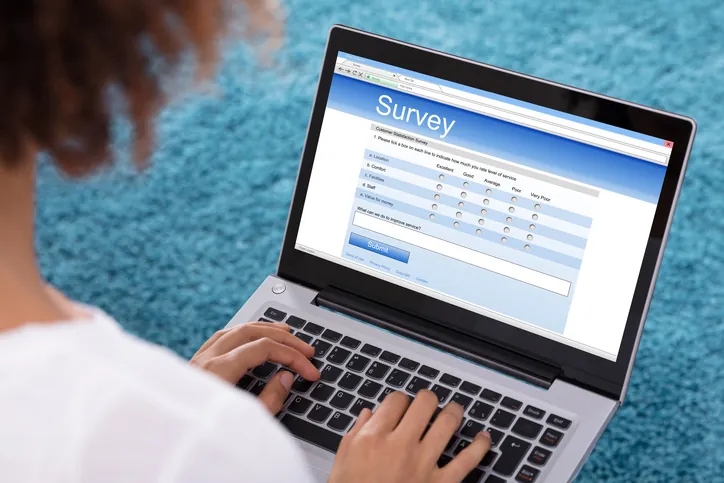 Woman typing on a laptop displaying a survey form