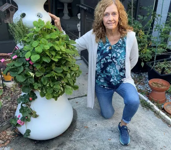 Lynn Cronin kneeling beside a large potted plant