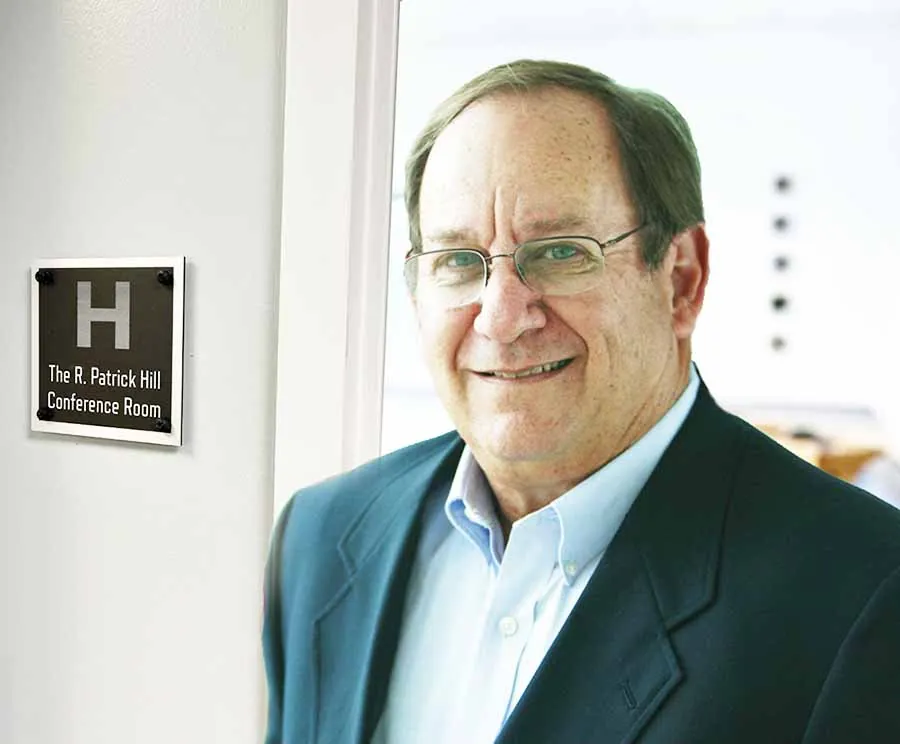 R. Patrick Hill standing beside the conference room named in his honor at HCP Associates