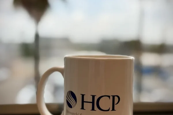 HCP Associates branded coffee mug on a windowsill