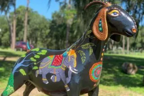Colorful painted goat sculpture displayed outdoors in a park