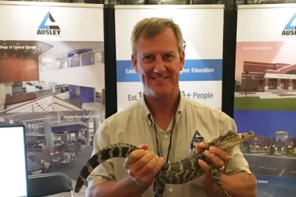 Todd Duffy Holding a gator in front of the Ausley Trade Show Booth at Florida Educational Facilities Planners Association FEFPA Summer Conference in Boca Raton