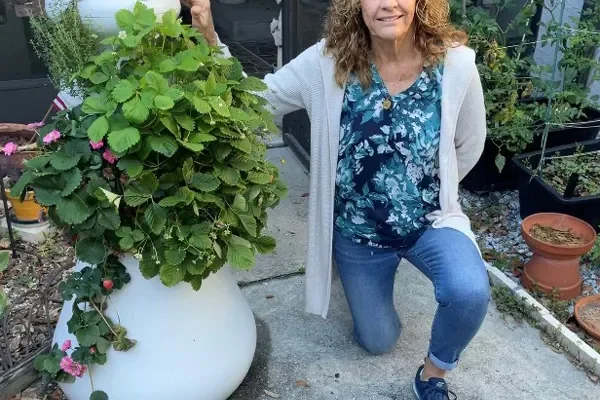Lynn Cronin kneeling beside a large potted plant