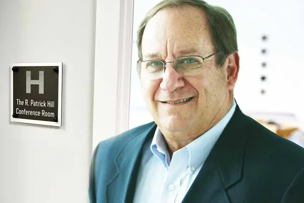 R. Patrick Hill standing beside the conference room named in his honor at HCP Associates