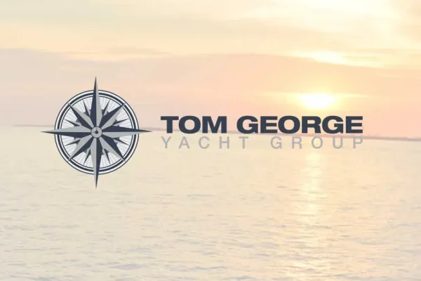 Tom George Yacht Group logo over a sunset over water