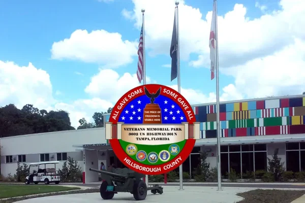 Government building with American and state flags, and a round commemorative emblem in front