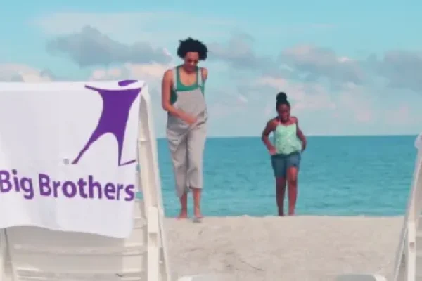 Big Brothers Big Sisters banner on a beach with two people in the background